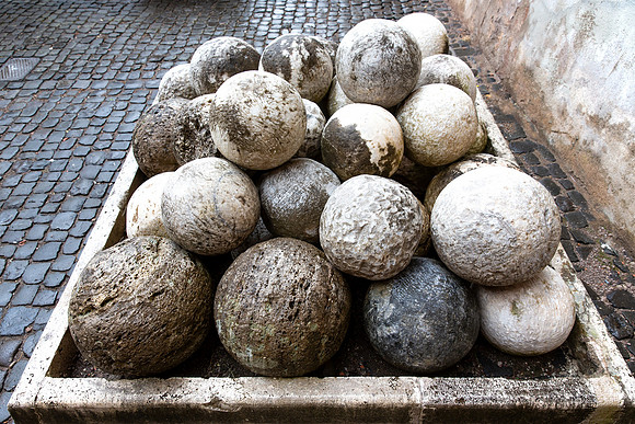 19.0 MB, 5184 x 3456: Old stone canon balls stacked in a holding bin in Italy.