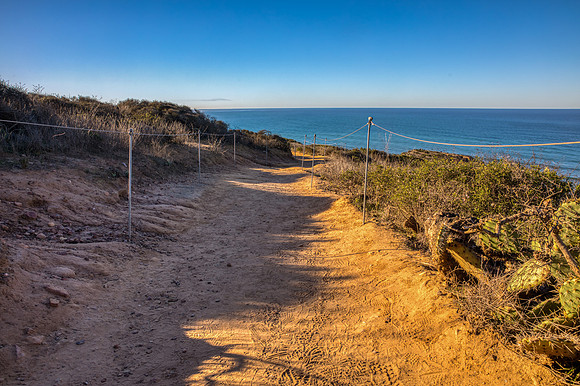 22.5 MB, 6699 x 4463: Brown dirt and sand hiking path leading to the blue Pacific ocean.