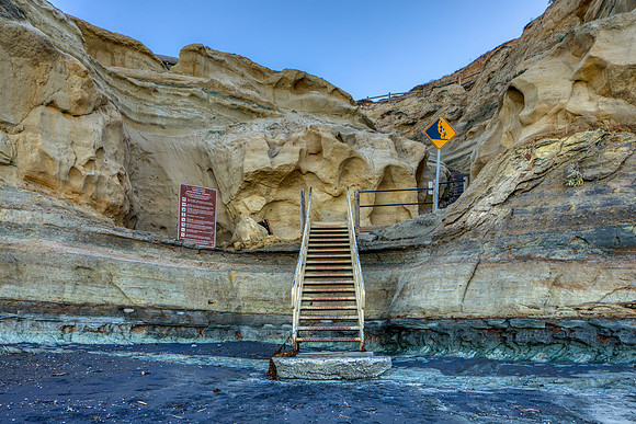 27.9 MB, 6720 x 4480: Stairs provide a path for hikers to ascend from the beach up the brown cliffs.
