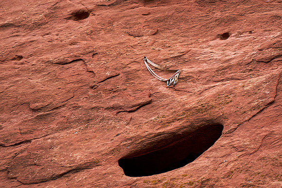 24.4 MB, 5042 x 3362: Climbing carabiner connected to a slack rope bolted to the a red rock wall